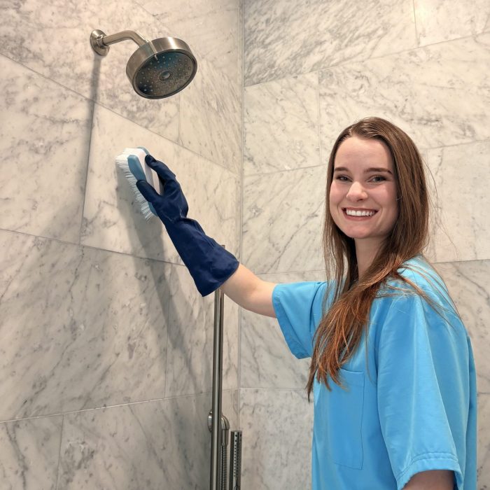 Professional cleaner removing hard-water buildup from a shower